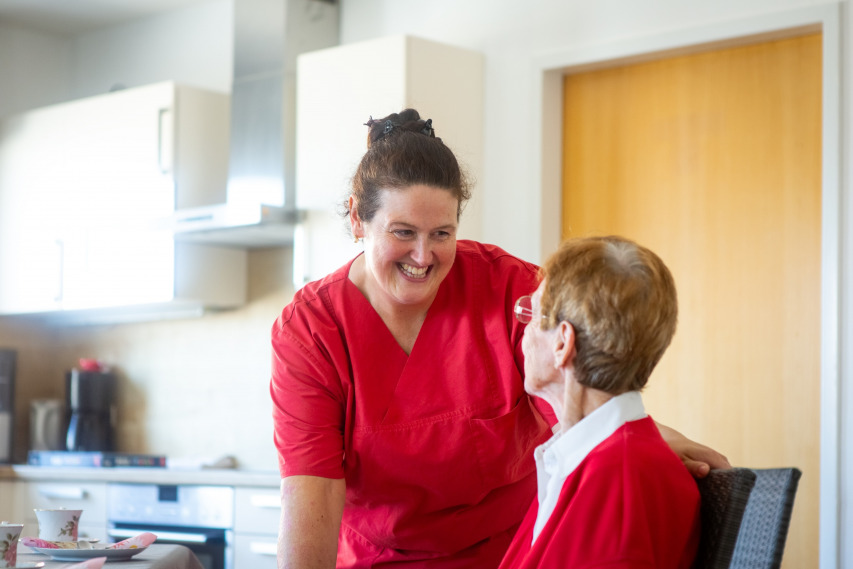 Eine Mitarbeiterin im Gespräch mit einer Seniorin