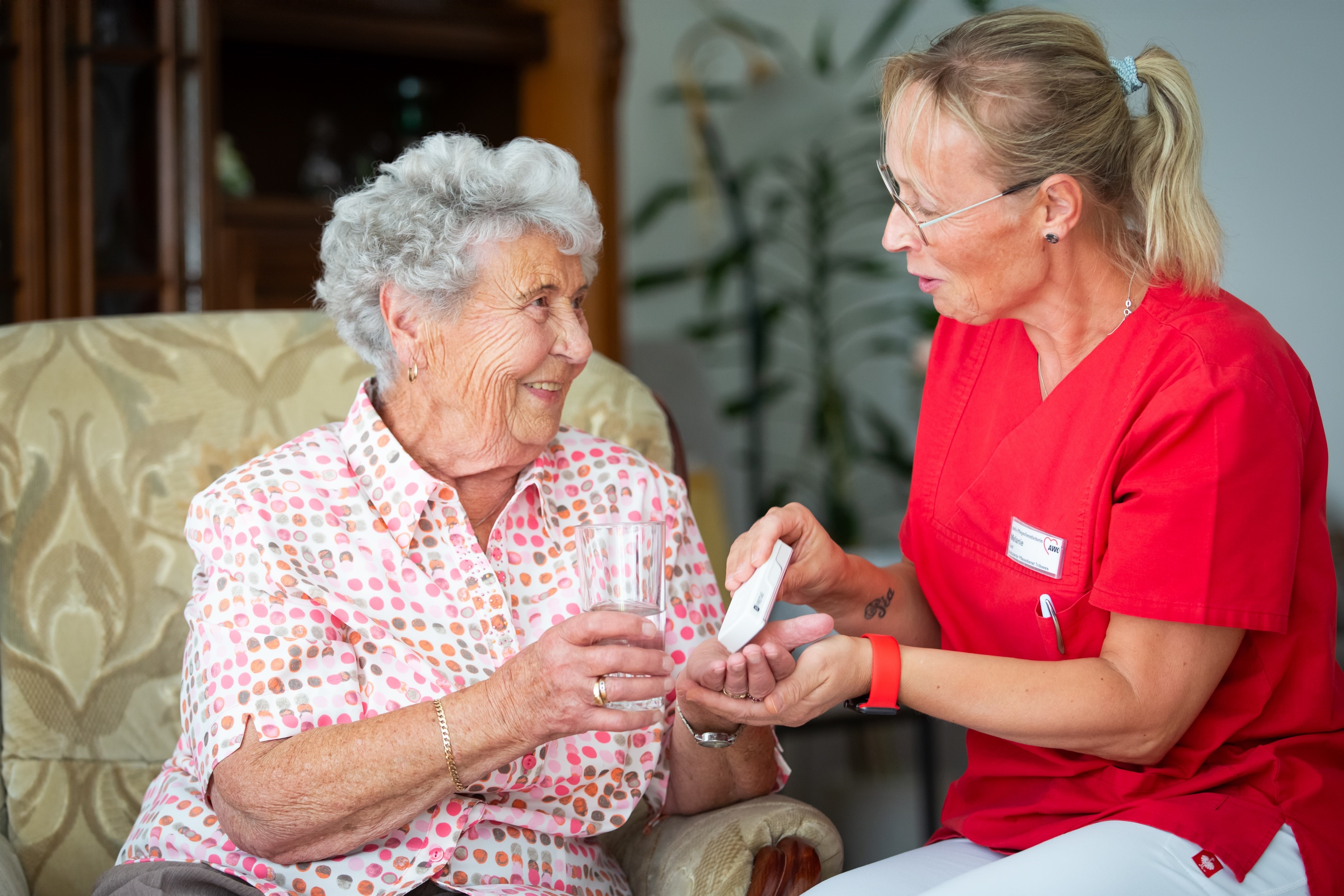 Eine Mitarbeiterin gibt einer Seniorin ihre Tabletten
